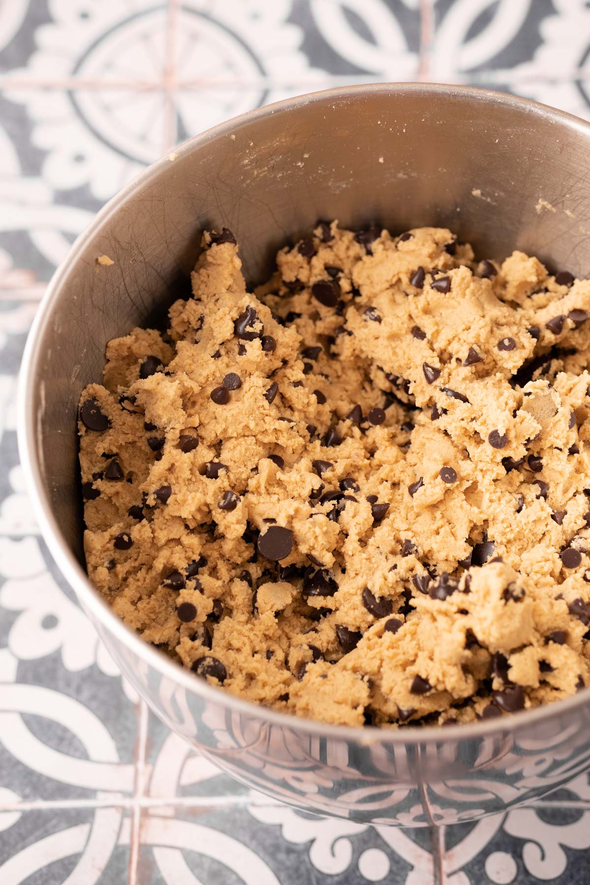 Cookie dough in a stainless steel mixing bowl.
