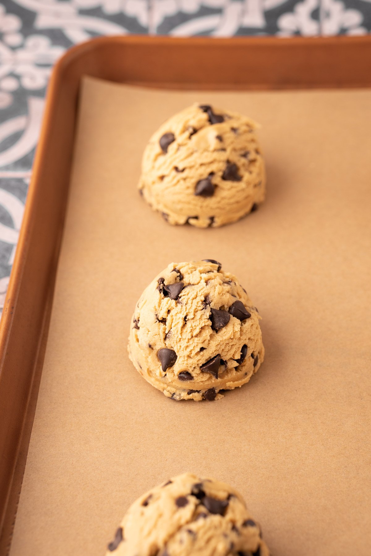 Balls of cookie dough on a parchment lined baking sheet.