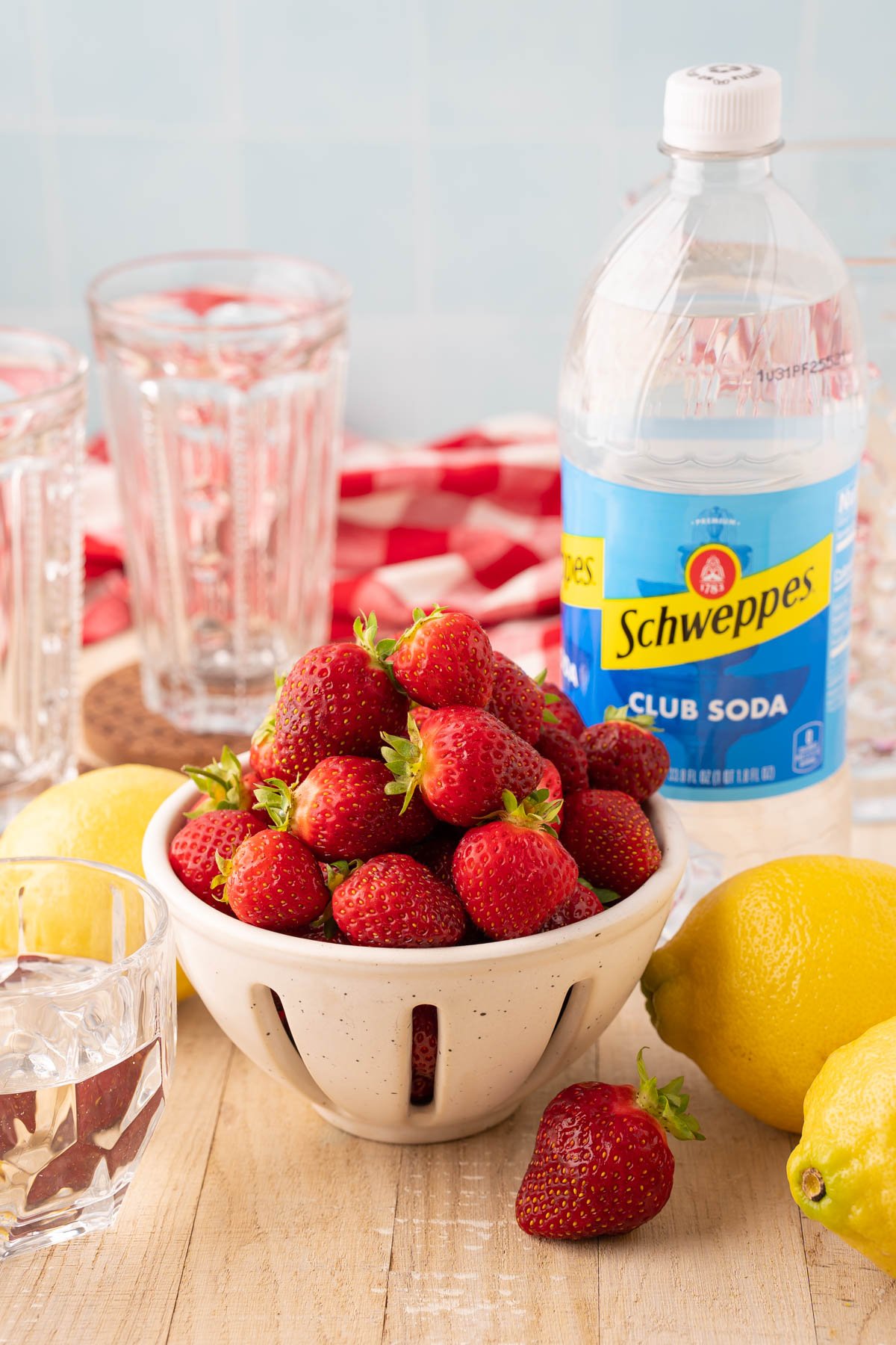 Ingredients to make strawberry lemonade on a wooden table.