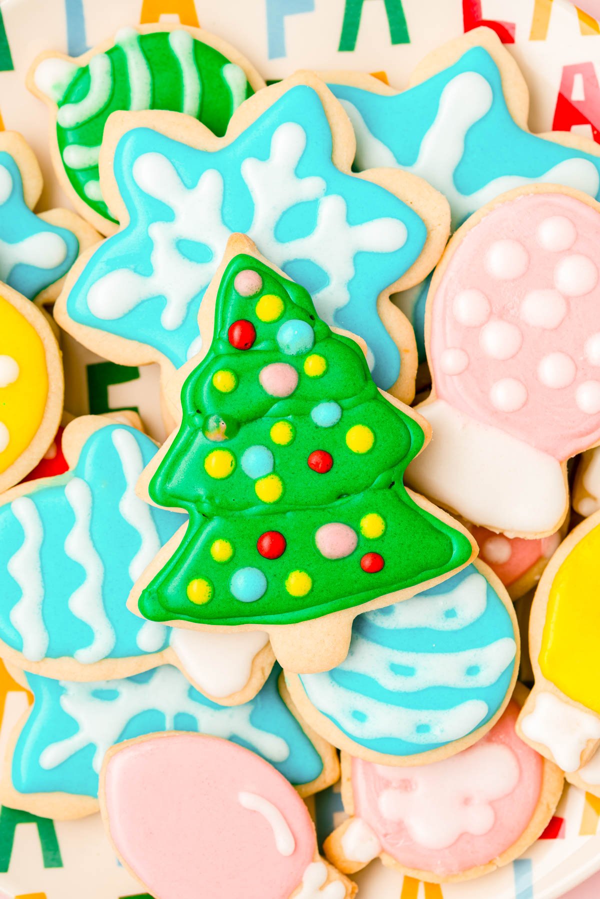 Royal iced sugar cookies for Christmas piled on a plate.