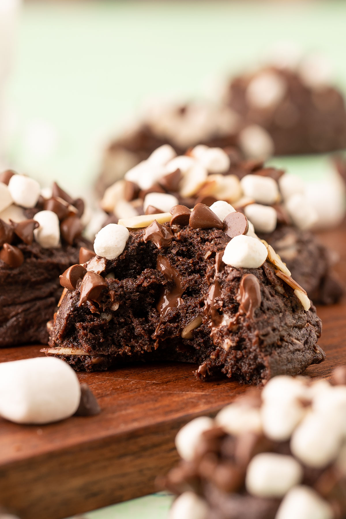 Rocky Road Cookie on a wooden board with a bite missing from it.