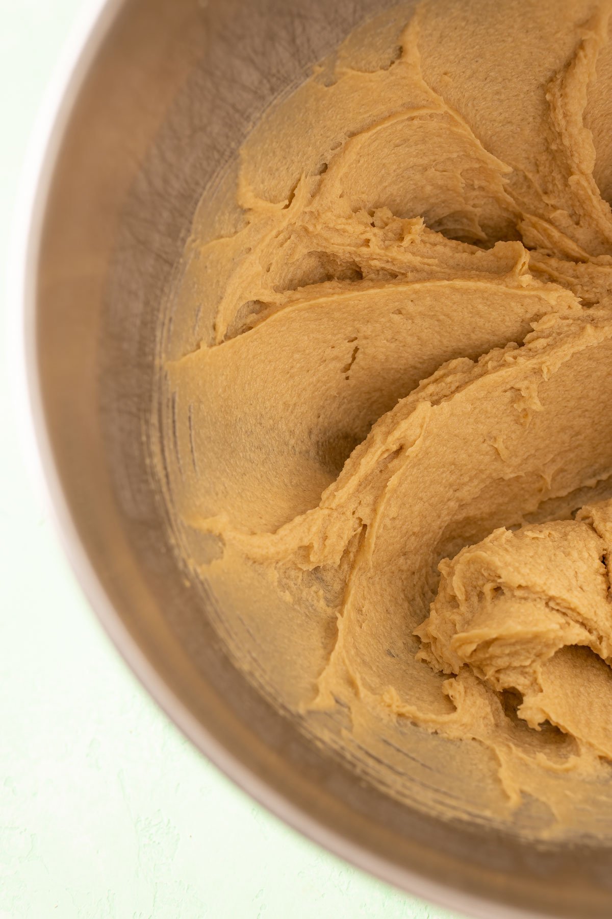 Butter, sugar, and eggs creamed in a stainless steel mixing bowl.