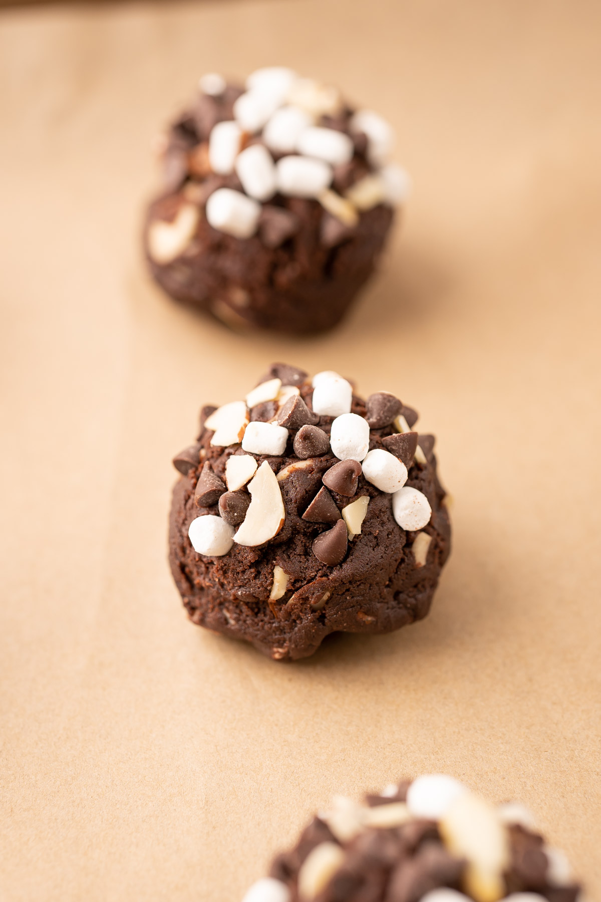 Balls of rocky road cookie dough on a piece of parchment paper.