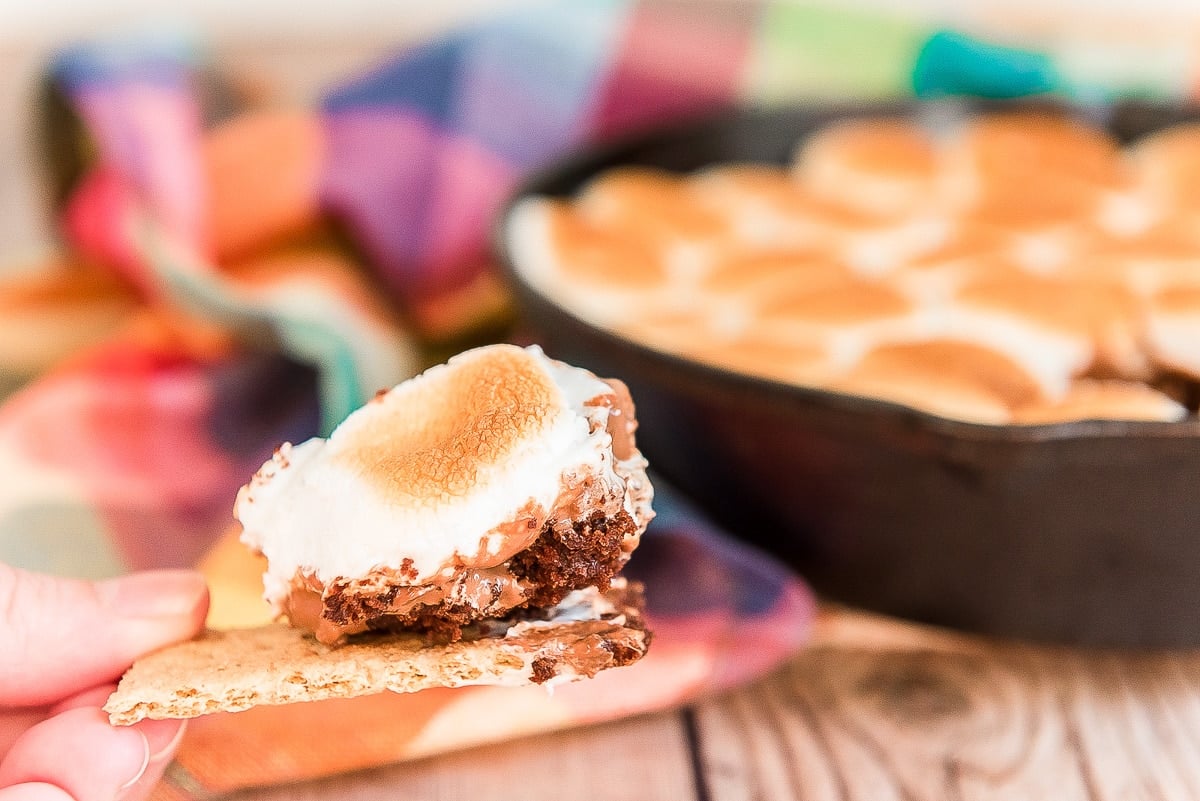 Close up photo of a bite of brownie s'mores dip on a graham cracker.