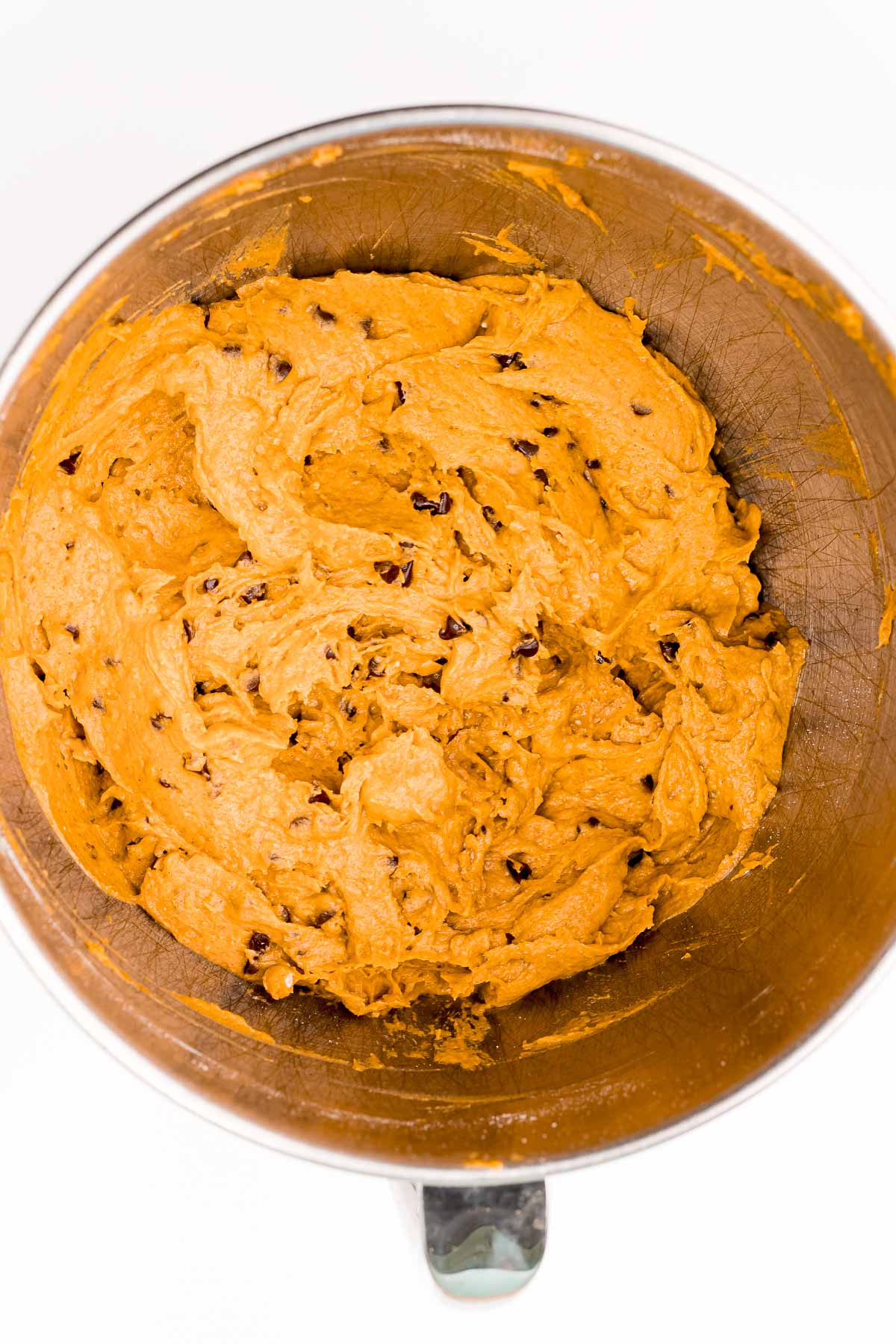 Overhead photo of mixing bowl filled with pumpkin chocolate chip cookie dough.
