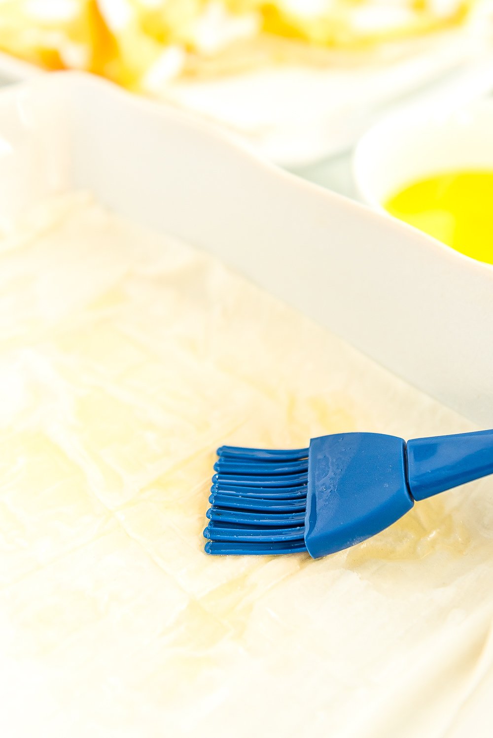 Pastry brush brushing butter onto phyllo dough.