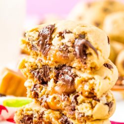 Close up photo of chocolate chip cookies stacked on top of each other that have caramel centers.