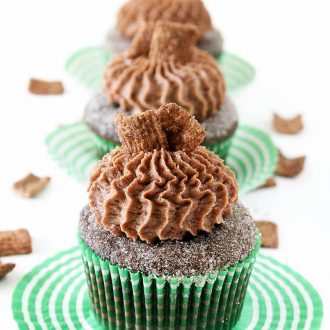 Three Frosted Cinnamon Toast Crunch cupcakes on striped coasters