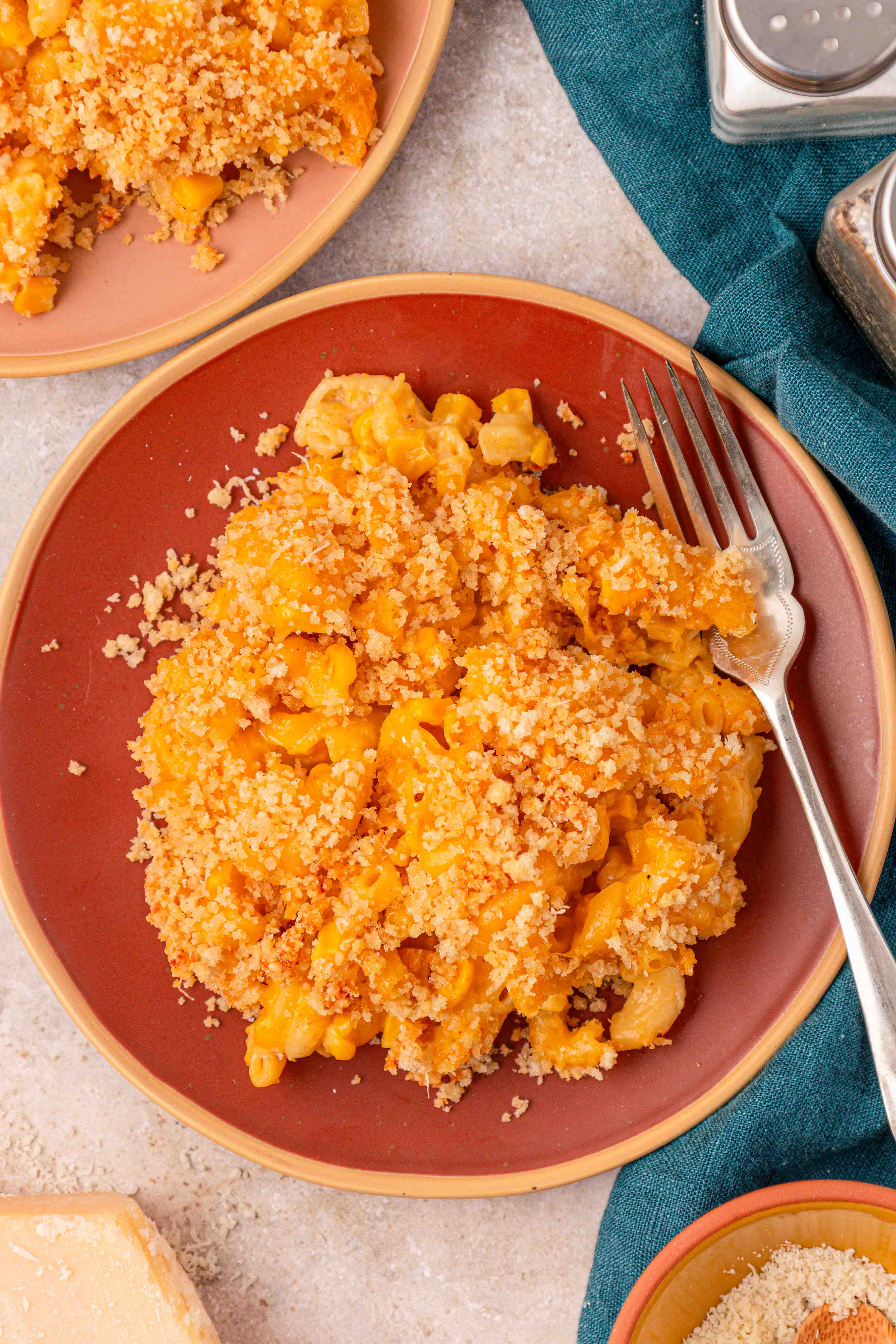 Overhead photo of a red plate with corn mac and cheese on it with a fork.