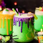 Close up photo of glasses of Halloween punch on a table with decorations scattered around.