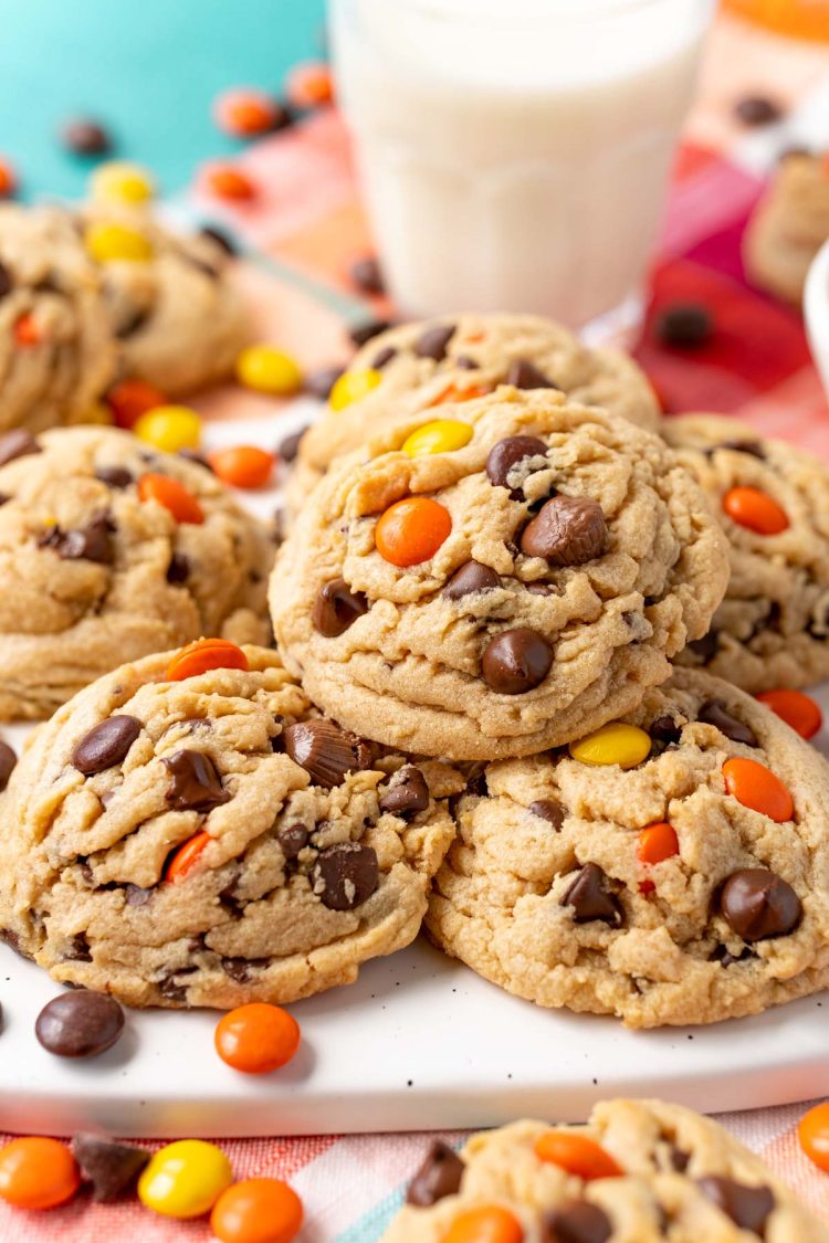 Close up of a peanut butter reese's pieces chocolate chip cookie on more cookies.