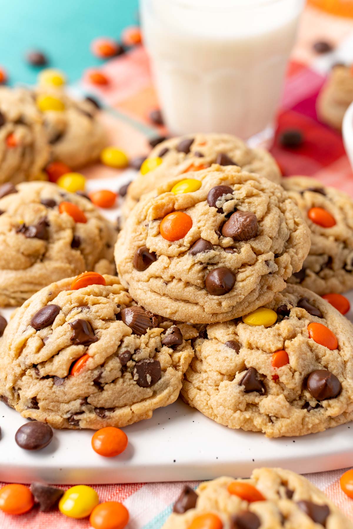 Close up of a peanut butter reese's pieces chocolate chip cookie on more cookies.