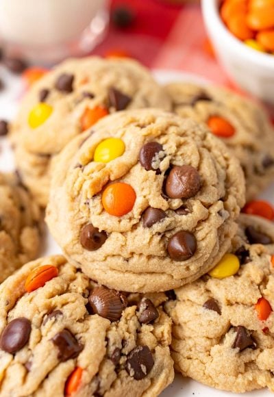 Close up of a peanut butter reese's pieces chocolate chip cookie on more cookies.