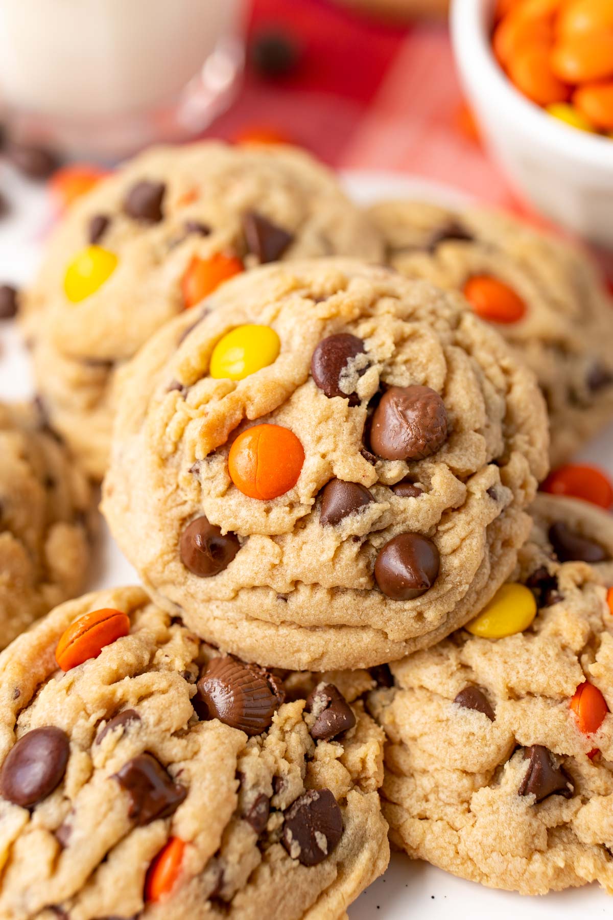 Close up of a peanut butter reese's pieces chocolate chip cookie on more cookies.