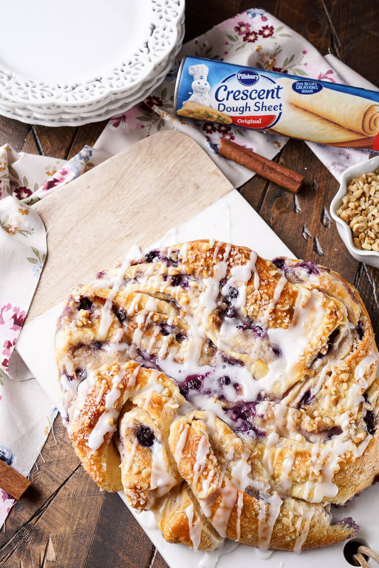 This Blueberry Spice Cream Cheese Breakfast Ring is the perfect addition to a holiday brunch. A simple and sweet filling is wrapped up in crescent dough and topped with chopped pecans and icing for a delicious morning pastry the whole family can enjoy!