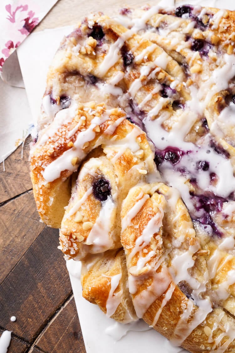 This Blueberry Spice Cream Cheese Breakfast Ring is the perfect addition to a holiday brunch. A simple and sweet filling is wrapped up in crescent dough and topped with chopped pecans and icing for a delicious morning pastry the whole family can enjoy!