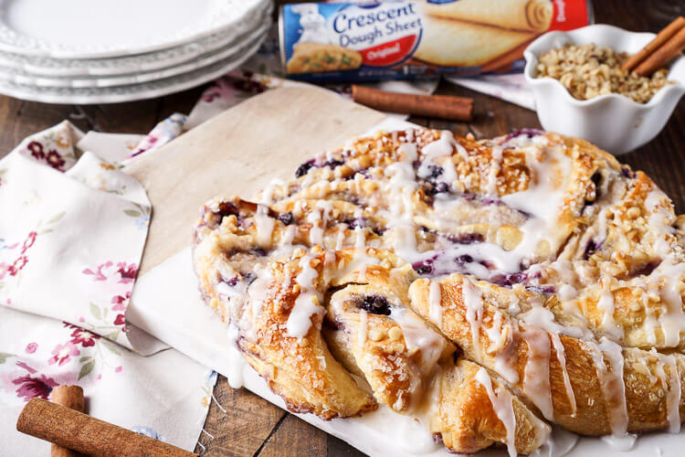 This Blueberry Spice Cream Cheese Breakfast Ring is the perfect addition to a holiday brunch. A simple and sweet filling is wrapped up in crescent dough and topped with chopped pecans and icing for a delicious morning pastry the whole family can enjoy!