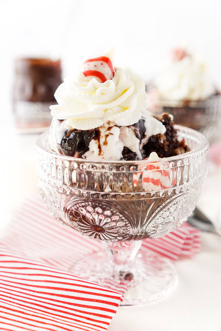 These Peppermint Kisses Brownie Sundaes are a dessert the whole family can make and enjoy together! Homemade fudgy brownies laced with Hershey's Candy Cane Kisses and topped with peppermint ice cream, whipped cream, and hot fudge make this a holiday treat you'll want to make again and again!