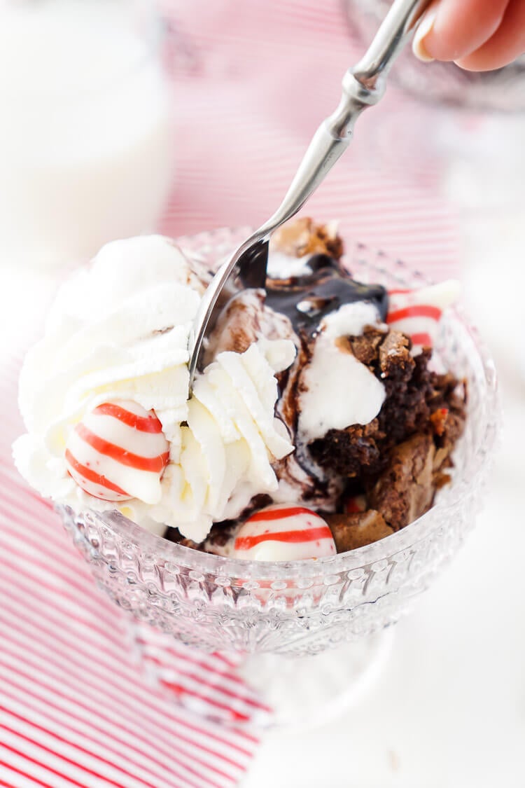 These Peppermint Kisses Brownie Sundaes are a dessert the whole family can make and enjoy together! Homemade fudgy brownies laced with Hershey's Candy Cane Kisses and topped with peppermint ice cream, whipped cream, and hot fudge make this a holiday treat you'll want to make again and again!