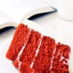Red Velvet Cake on Plate next to open book and glass of milk