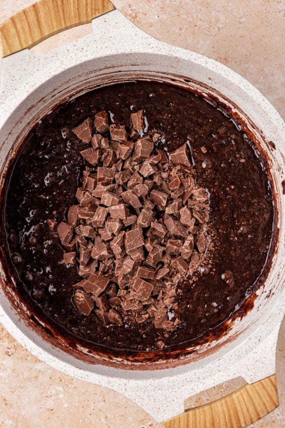 Chocolate chunks being added to a pot of brownie batter.