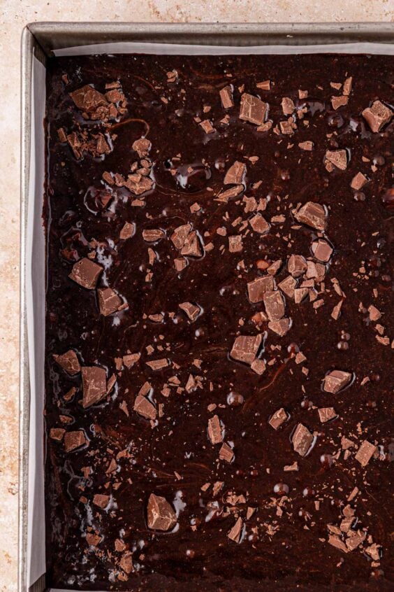 Brownie batter in a 9x13-inch pan topped with chocolate chunks.