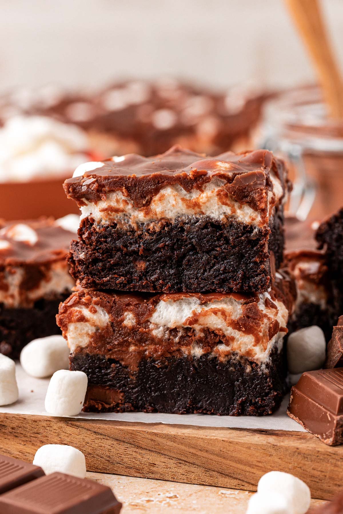 A stack of two brownies topped with marshmallows and chocolate icing.