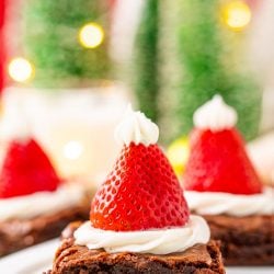 Close up photo of square brownies decorated with frosting and strawberries to look like santa hats.