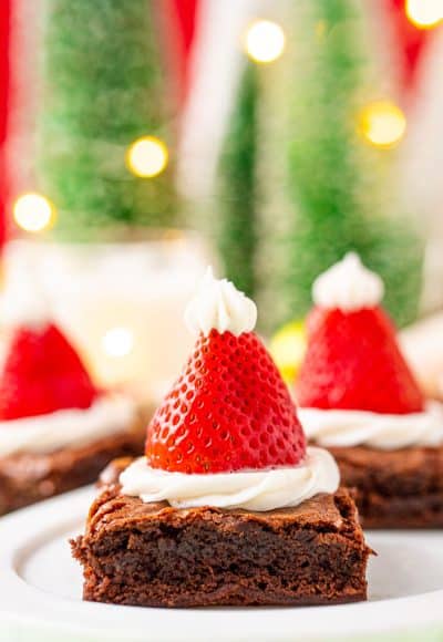Close up photo of square brownies decorated with frosting and strawberries to look like santa hats.