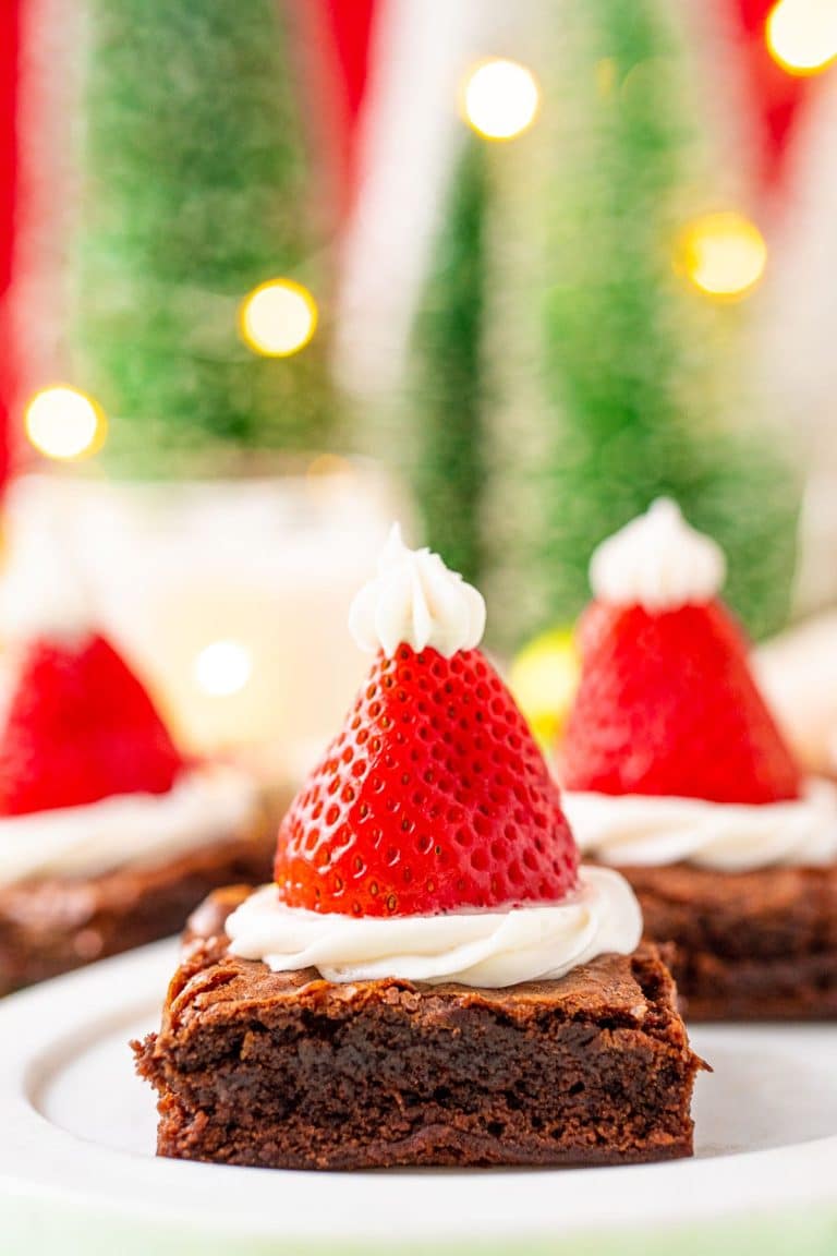 Close up photo of square brownies decorated with frosting and strawberries to look like santa hats.