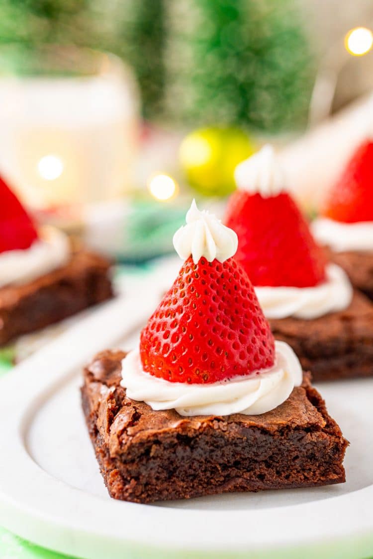 Close up photo of a serving tray with santa hat decorated brownies on it for a holiday party.