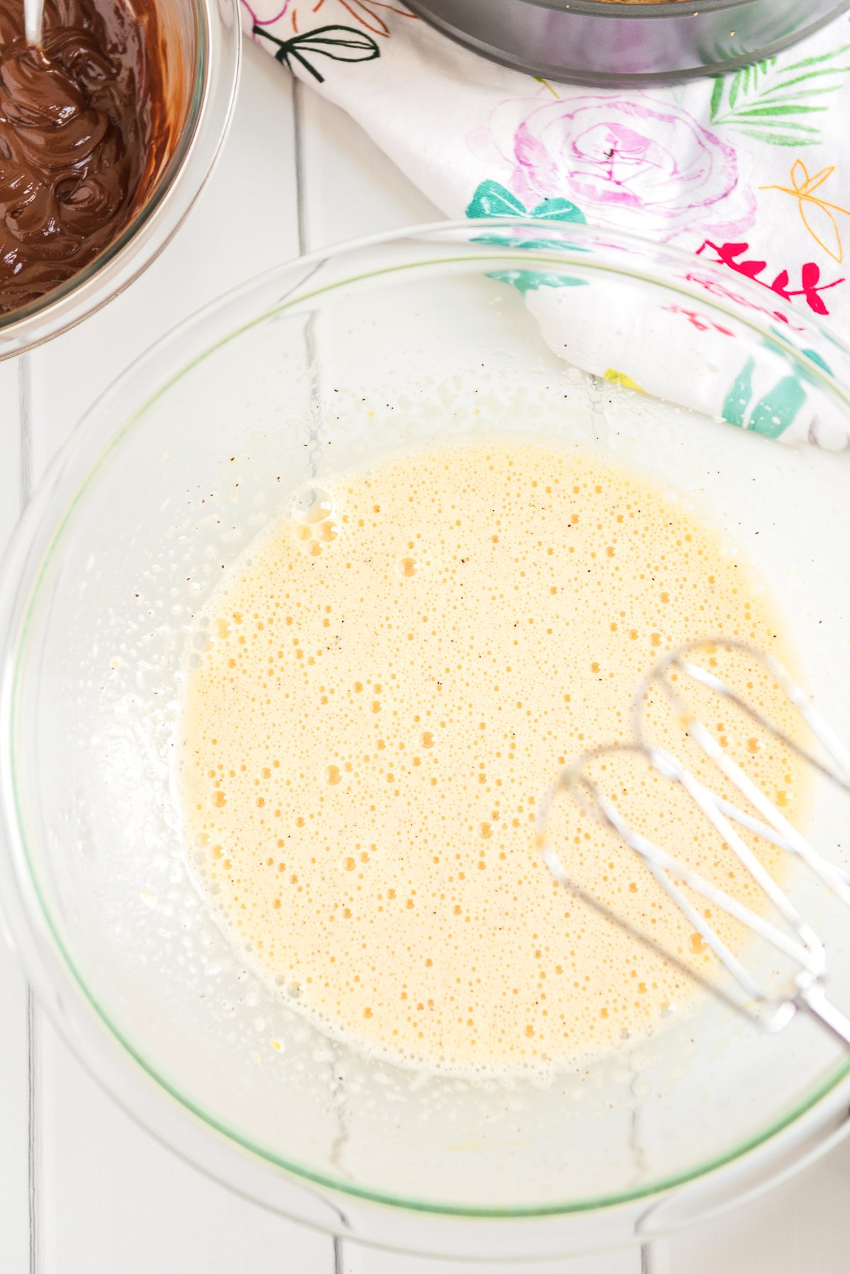 Eggs, sugar, coffee granules, and vanilla that have been beaten together in a glass mixing bowl