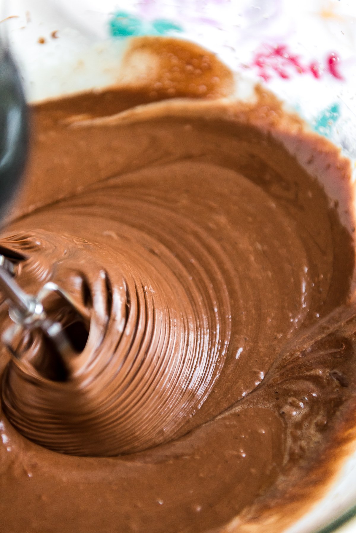 Brownie batter being mixed with a hand mixer.