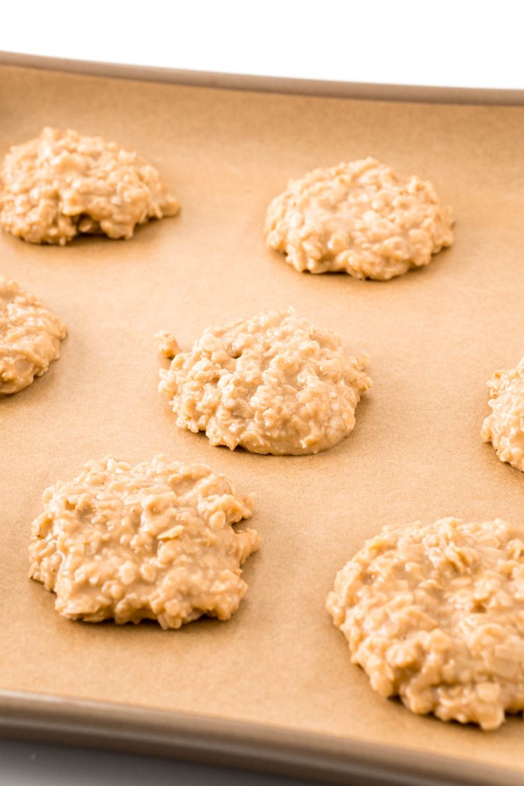Peanut butter no bake cookies on a parchment lined baking sheet.