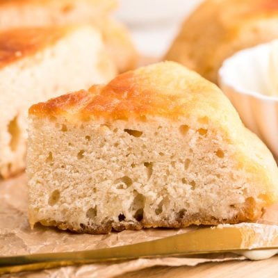 Close up photo of a slice of Bannock bread on a piece of parchment on a wooden cutting board.