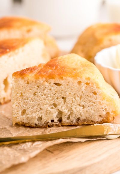 Close up photo of a slice of Bannock bread on a piece of parchment on a wooden cutting board.