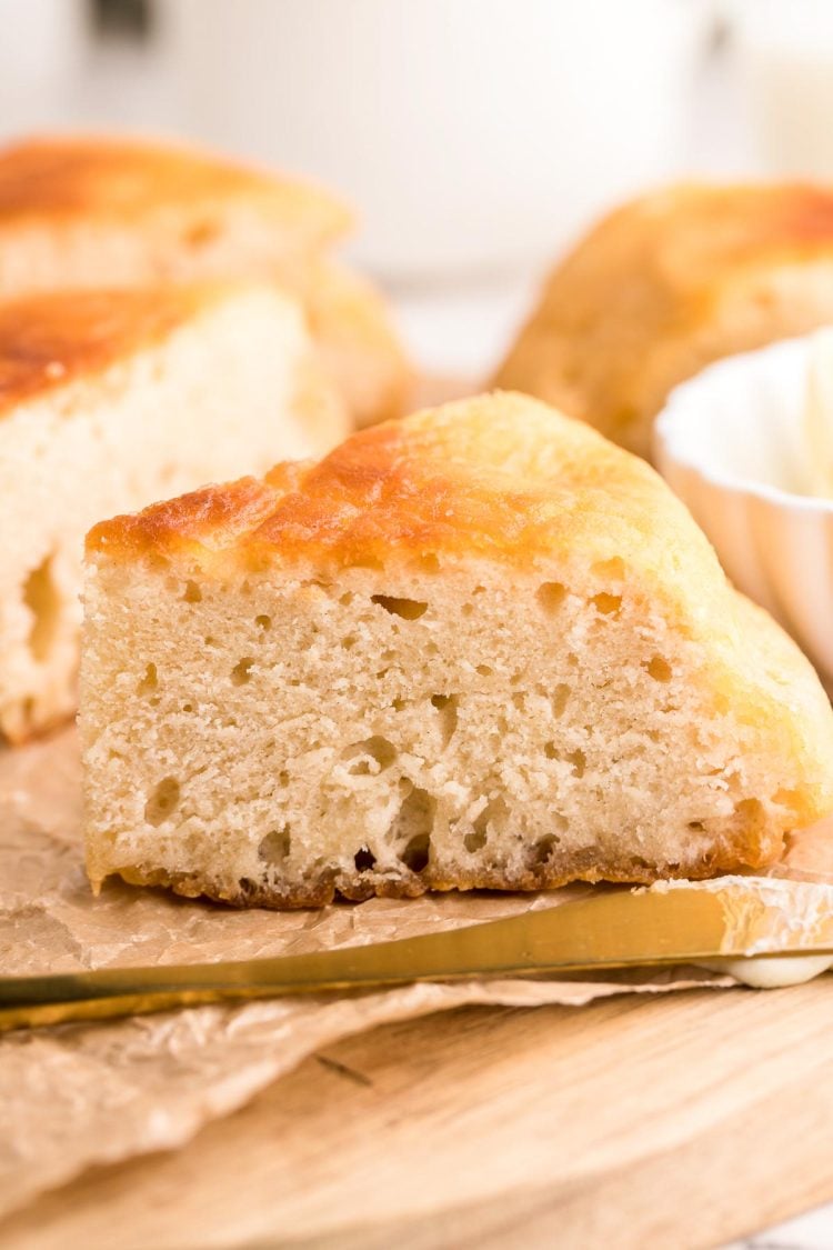 Close up photo of a slice of Bannock bread on a piece of parchment on a wooden cutting board.