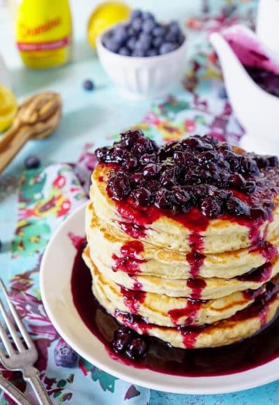 These Lemon Ricotta Pancakes are fluffy and laced with zest, then topped with a homemade Blueberry Honey Syrup for a sweet finish!