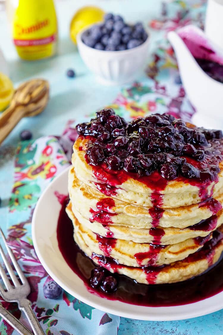 These Lemon Ricotta Pancakes are fluffy and laced with zest, then topped with a homemade Blueberry Honey Syrup for a sweet finish!