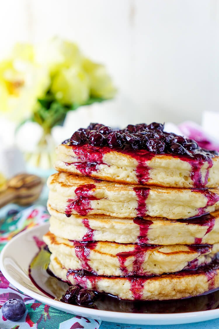 These Lemon Ricotta Pancakes are fluffy and laced with zest, then topped with a homemade Blueberry Honey Syrup for a sweet finish!