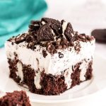 Close up photo of a piece of Oreo poke cake sitting on a white plate.