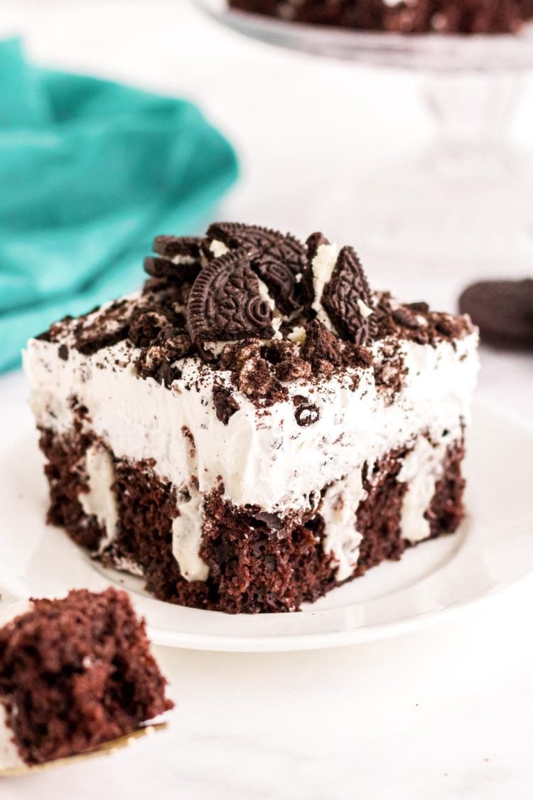 Close up photo of a piece of Oreo poke cake sitting on a white plate.