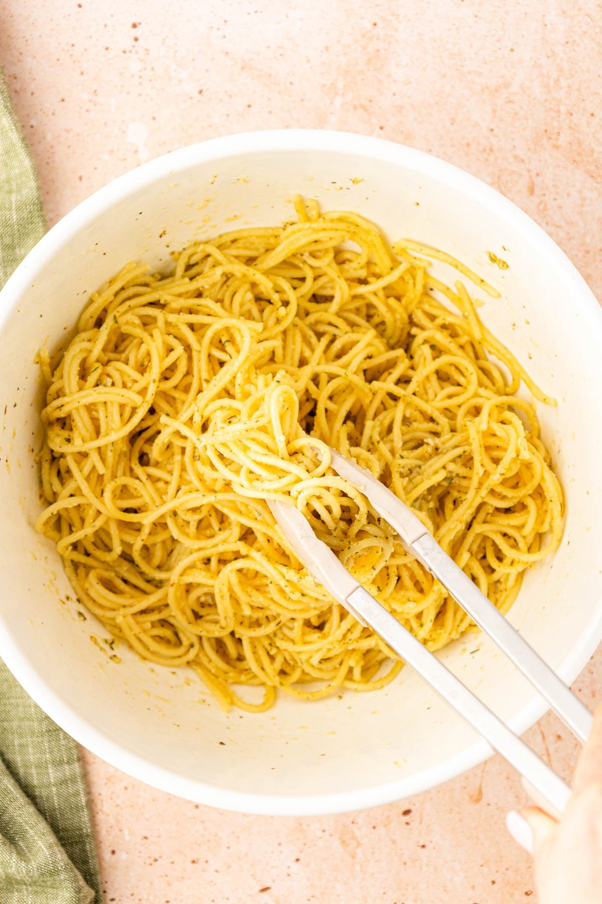 Pasta being tossed with egg, cheese, and spices.