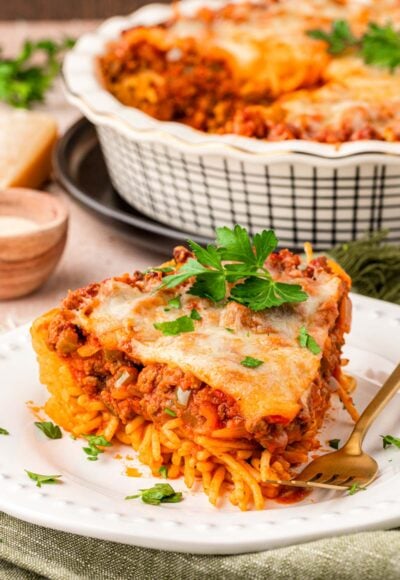 A slice of spaghetti pie on a white plate with a fork.