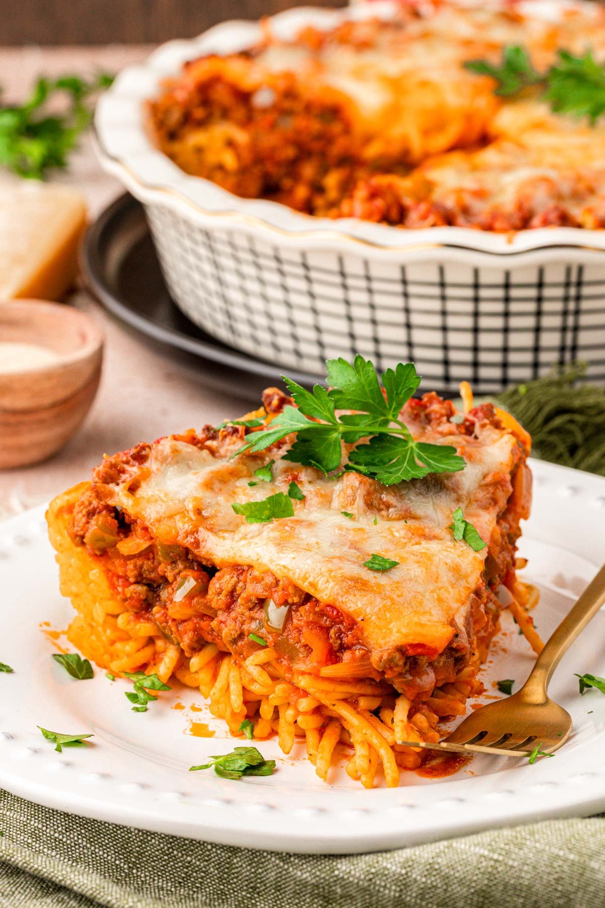 A slice of spaghetti pie on a white plate with a fork.