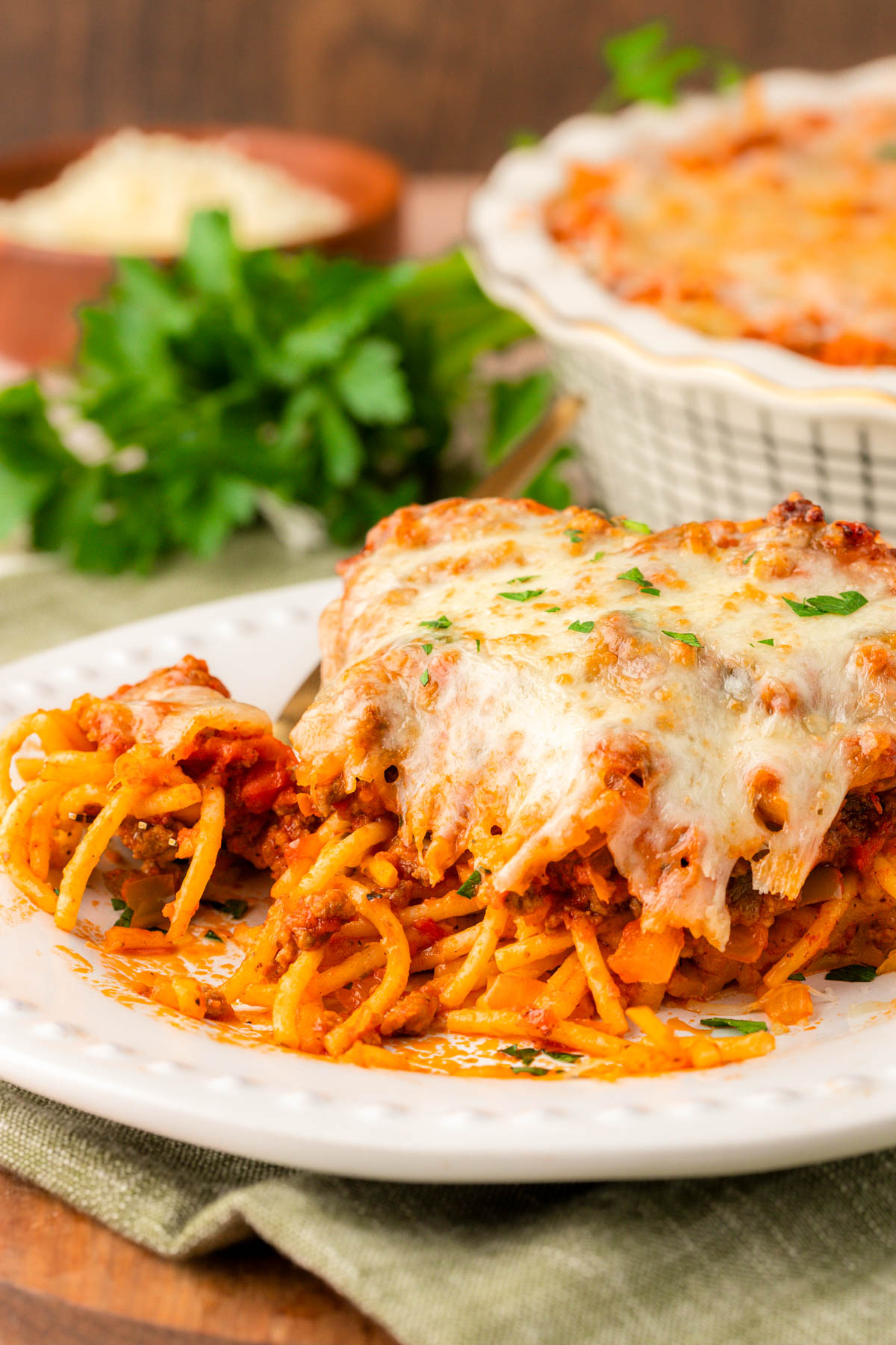 Spaghetti pie on a white plate with bites taken out.