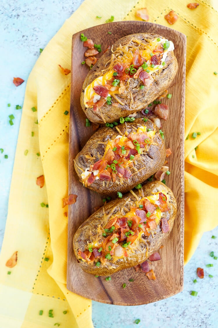 These are the Best Ever Baked Potatoes, they're perfectly seasoned and loaded up with a creamy dressing, cheddar cheese, bacon, and chives!