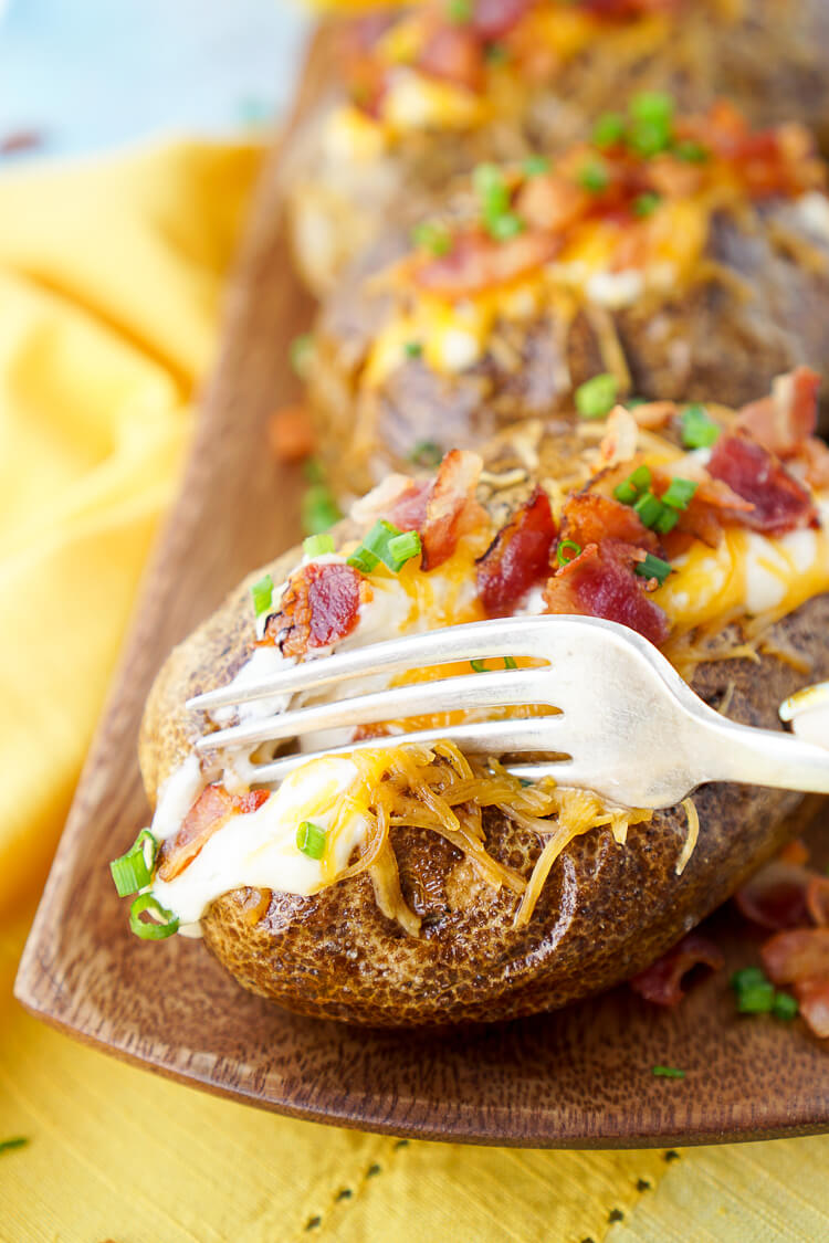 These are the Best Ever Baked Potatoes, they're perfectly seasoned and loaded up with a creamy dressing, cheddar cheese, bacon, and chives!