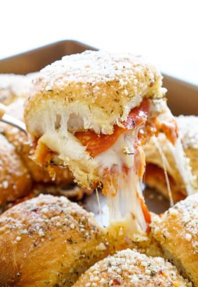 These Easy Pizza Sliders are so simple to make and are sure to be a family favorite! Layers of sauce, mozzarella, bacon, and pepperoni are baked in soft dinner rolls coated in butter, herbs, and parmesan!