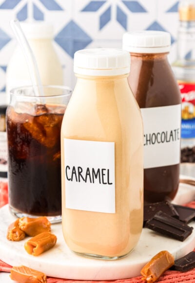 Bottles of homemade coffee creamer next to a glass of iced coffee.